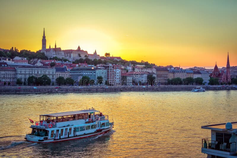 Budapest/Hungary- May 6, 2018: evening cityscape with Danube River, beautiful historic buildings and towers, touristic boats, colorful sunset sky and Buda Castle on horizon. Budapest/Hungary- May 6, 2018: evening cityscape with Danube River, beautiful historic buildings and towers, touristic boats, colorful sunset sky and Buda Castle on horizon.